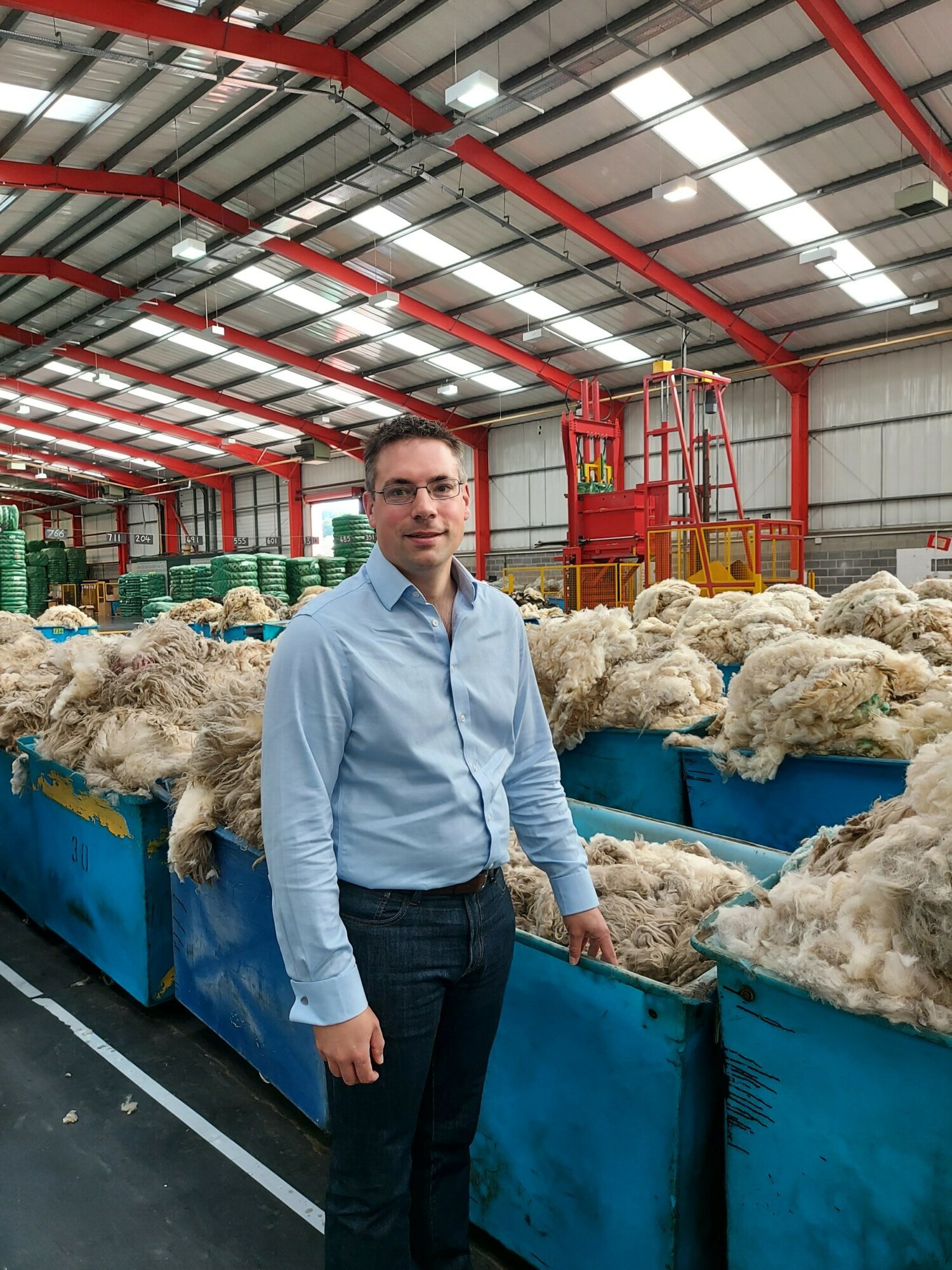 British Wool CEO, Andrew Hogley stood in front of bundles of wool. 