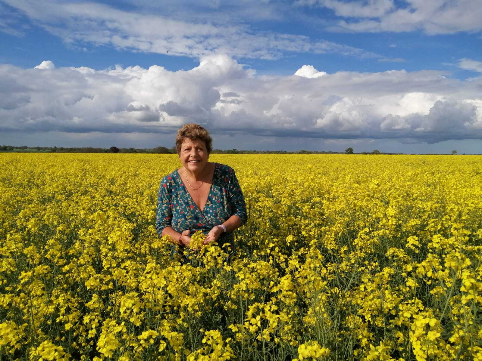 Rural business owner, Sally in a field of rapeseed flowers
