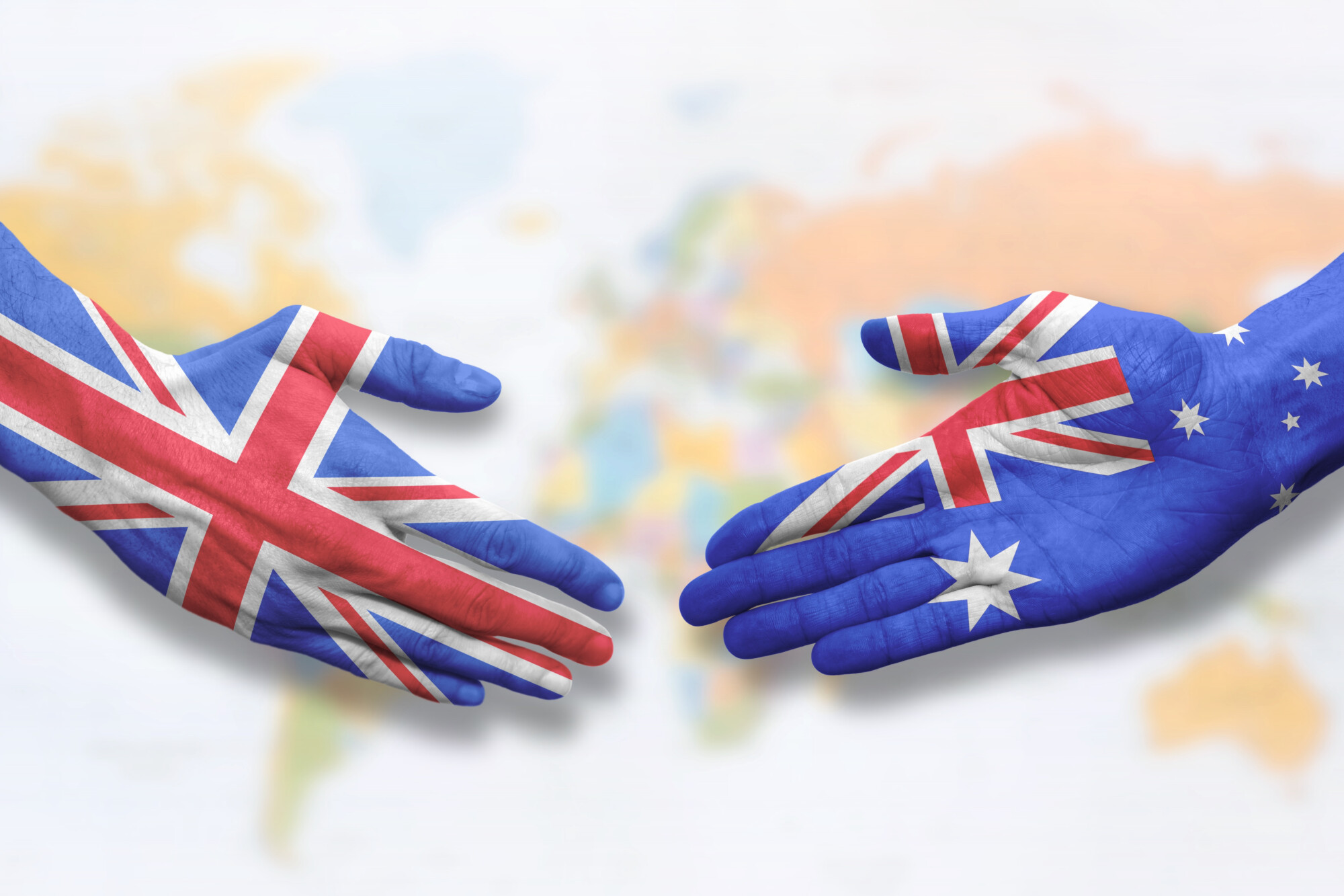 painted hands about to shake - one painted with a Great Britain flag and the other with an Australian flag representing the UK-Australia trade deal