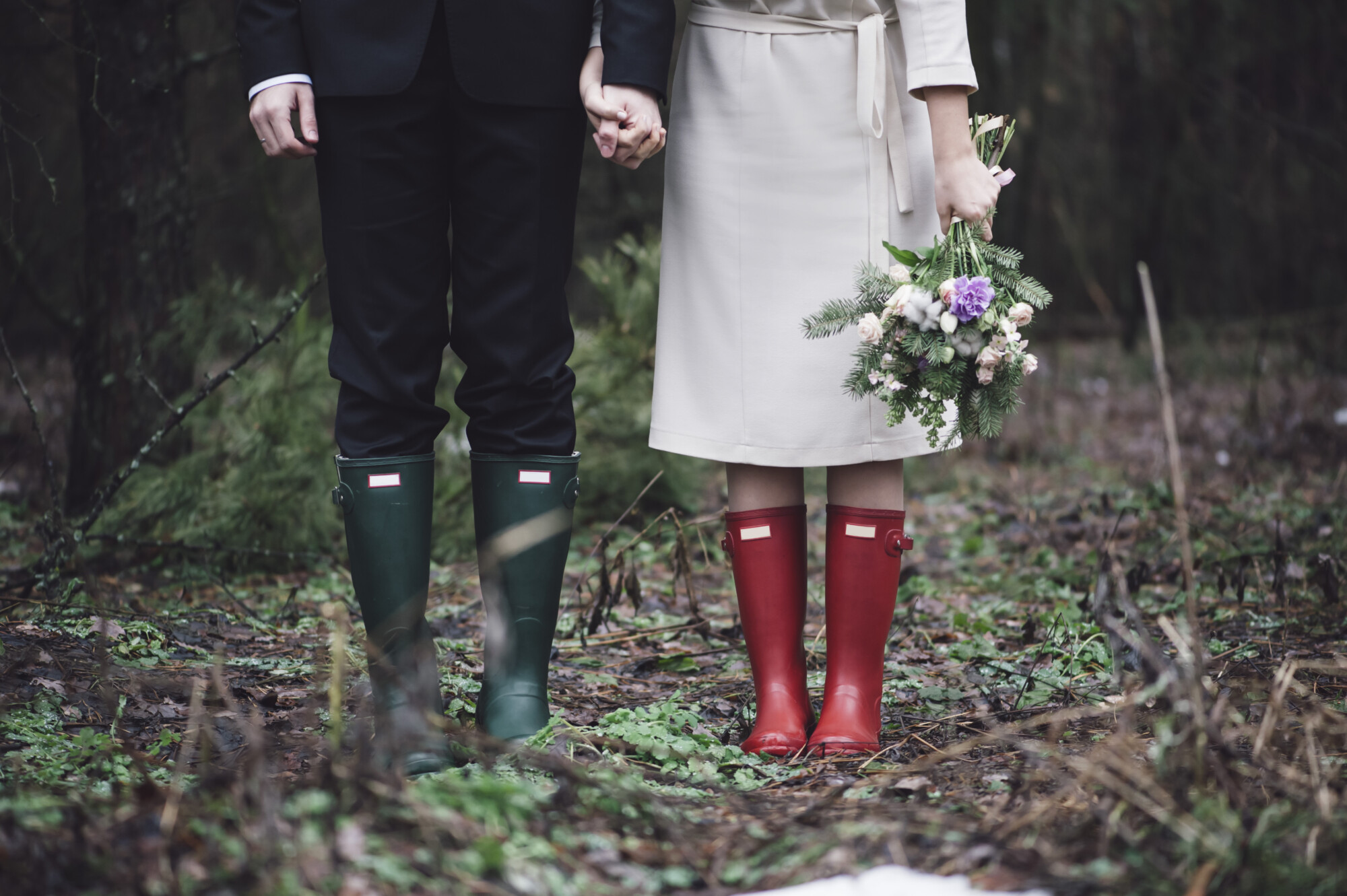Wedding couple standing in the forest wearing colourful rubber boots