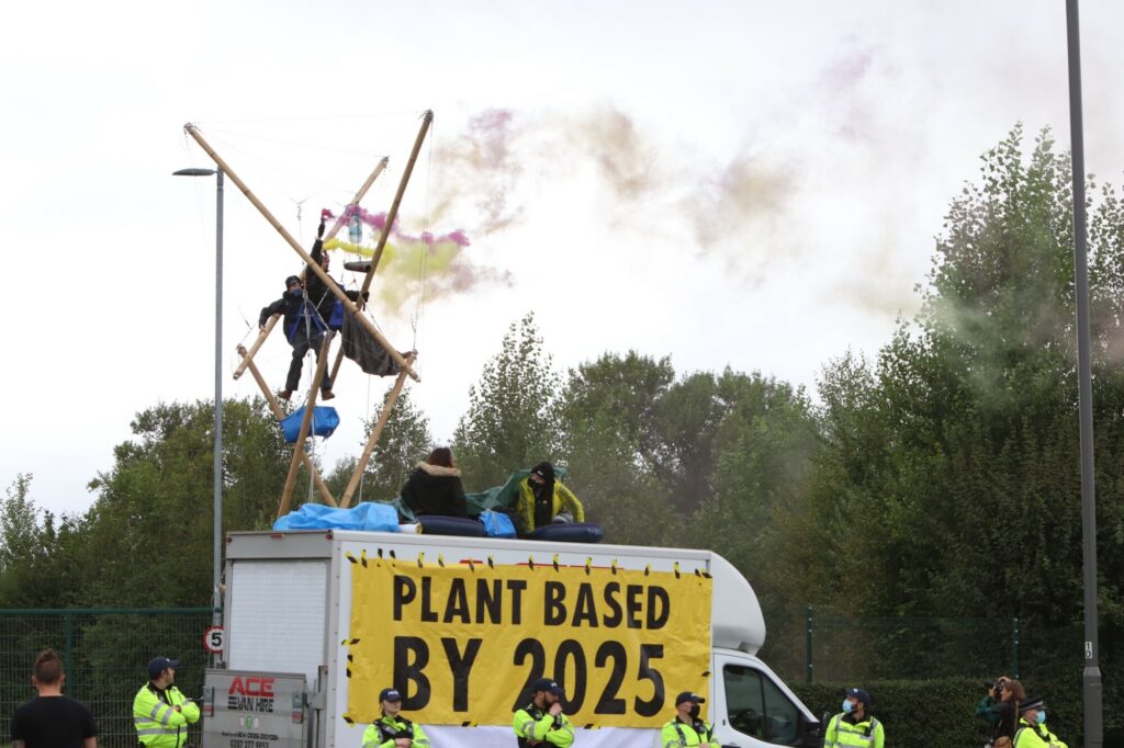 Animal Rebellion activists on bamboo structures surrounded by police at the UK's largest dairy factory
