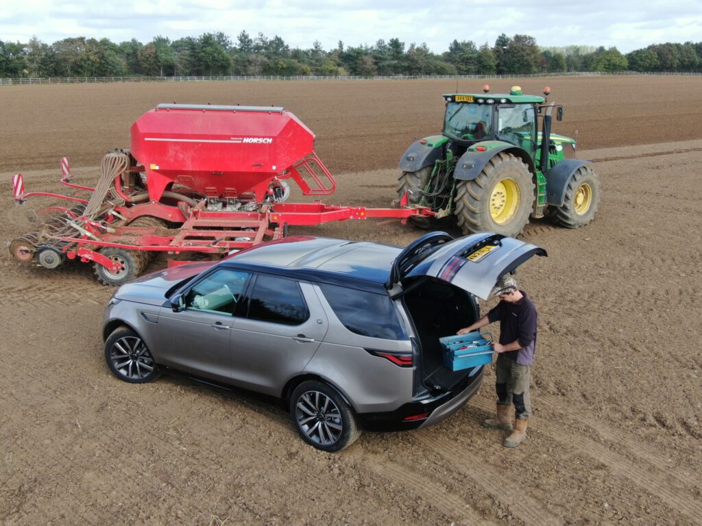 Land Rover in a field with tractor and machinery