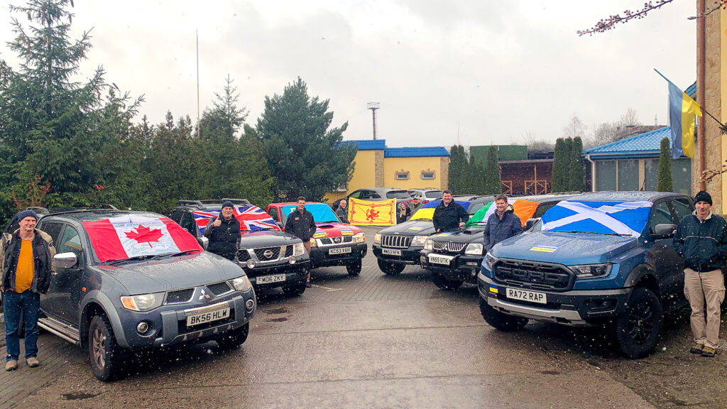 A line-up of six cars donated to Car for Ukraine, all decorated with the flag of the country they came from, including Canada, the UK, Ireland and Scotland. 