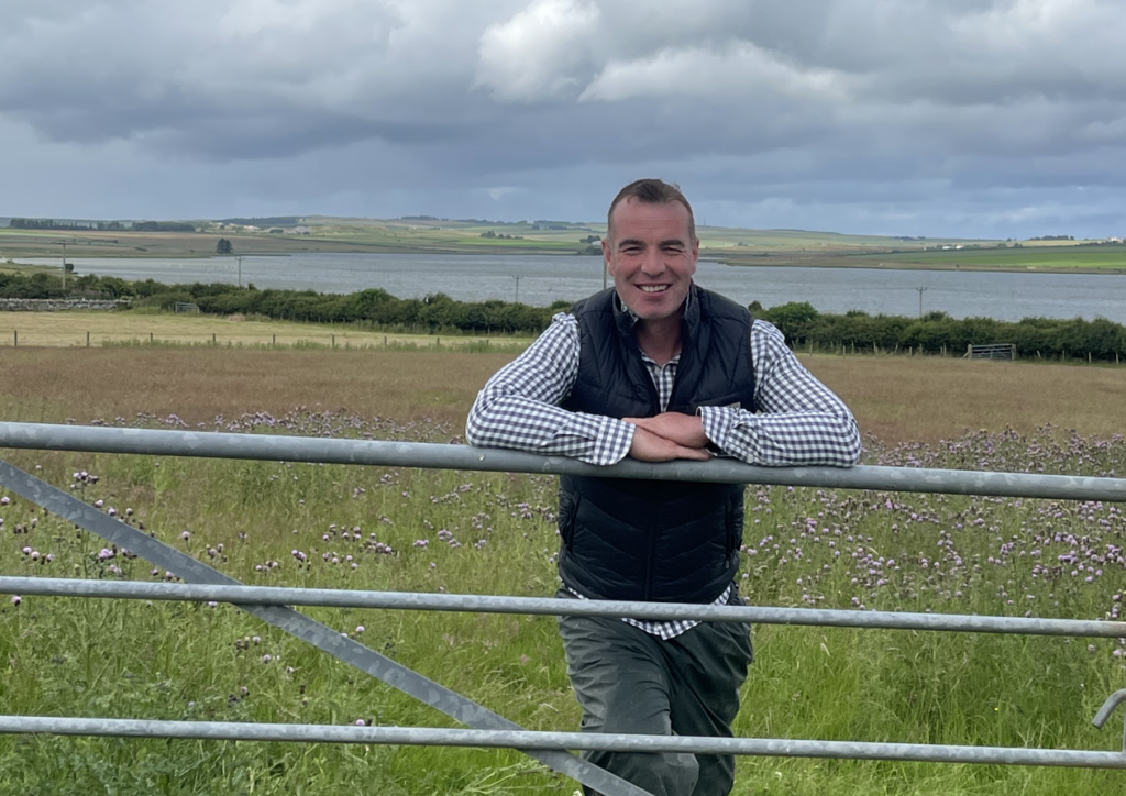 Beef farmer Donald Henderson, leaning against the gate with his farm in Wick, Caithness in the background.
