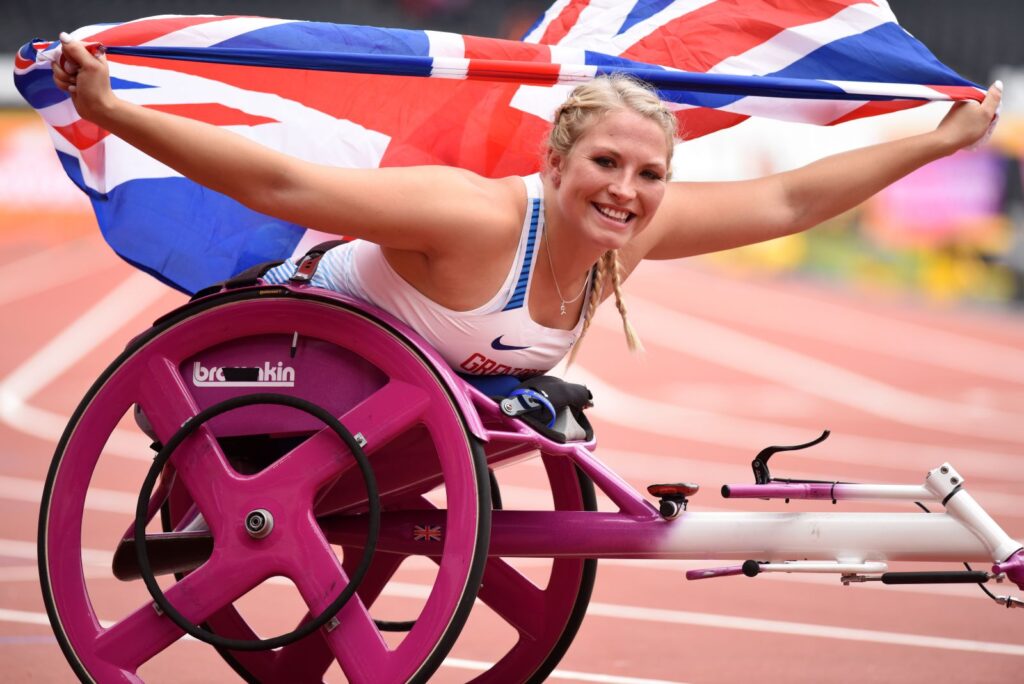Sammi Kinghorn holding union jack whilst in racing wheelchair