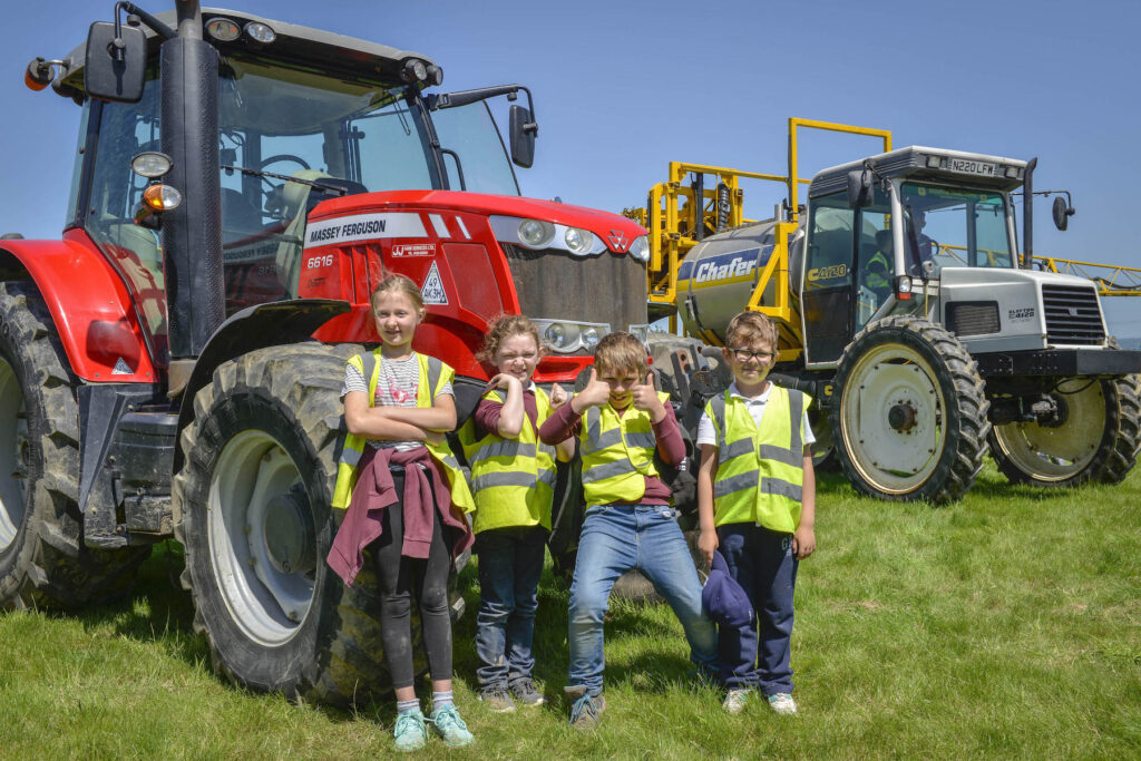 group of four children standing in front of tractor