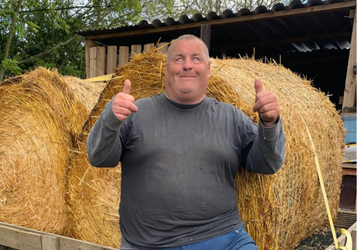 Mike co-owns inclusive Farm, helping students with disabilities find a way into agriculture. He is sitting next to two straw bales