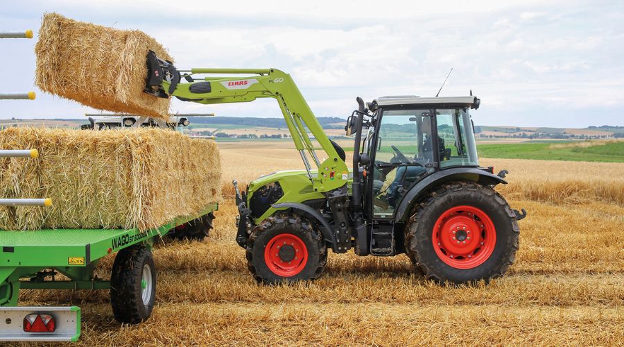 New Elios and Axos tractors with 75–103hp picking up hay bail onto flatbed