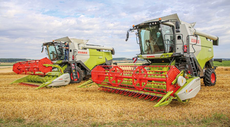 Claas Evion 410 and 430 combine harvesters green and red stationary in farmer's field