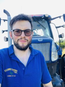 Tristan Corney, fifth generation arable farmer, standing in front of a tractor