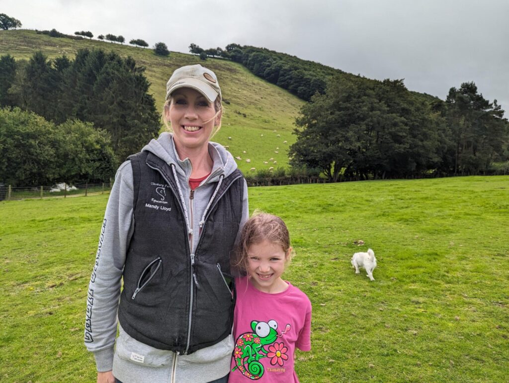 Mandy Lloyd with her young daughter and the farm in the background.