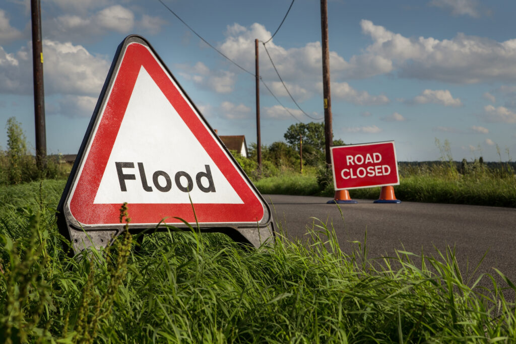 Sign on a country road reading 'road closed, flooding'