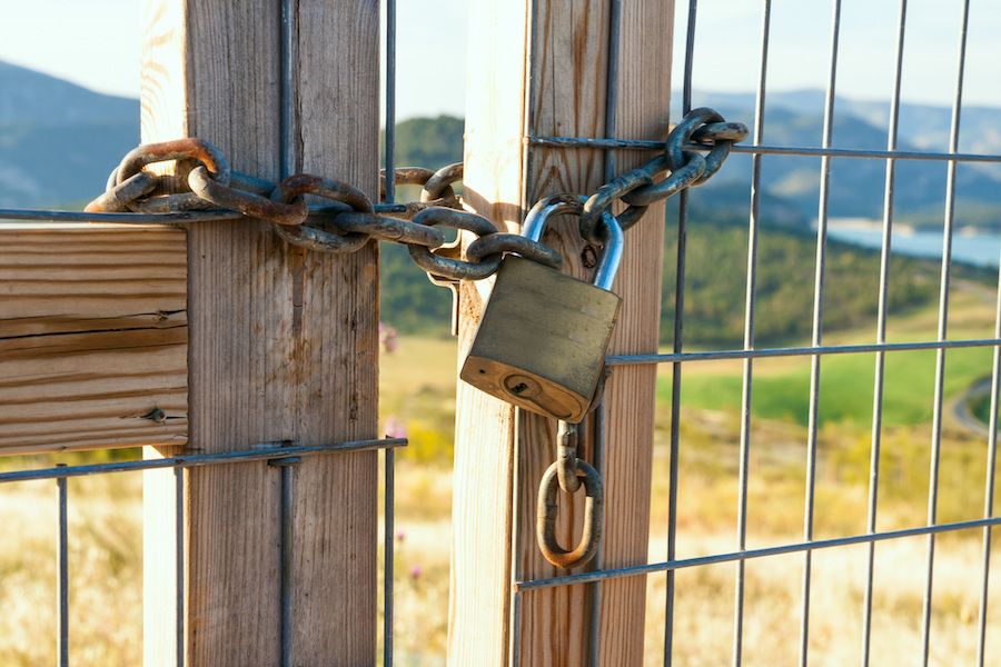 locked farm gate, with rural landscape in the background
