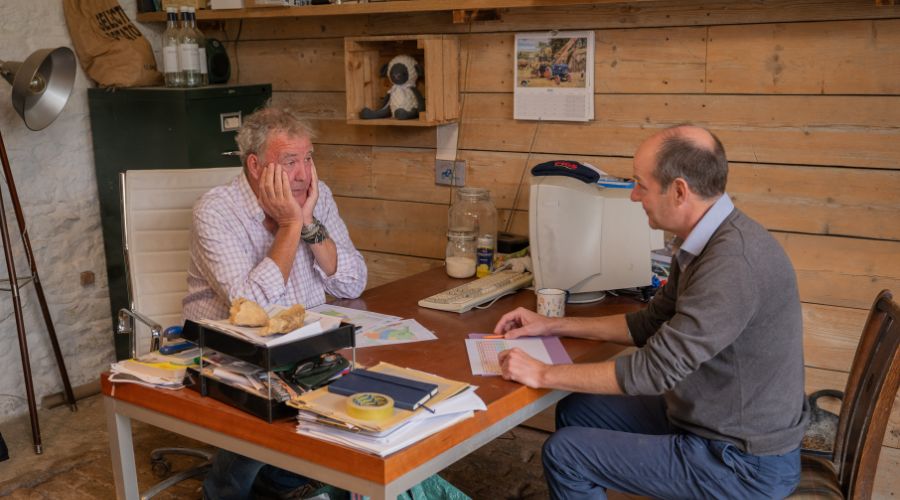 Jeremy Clarkson in his farm office with his head in his hands, sat opposite Charlie Ireland