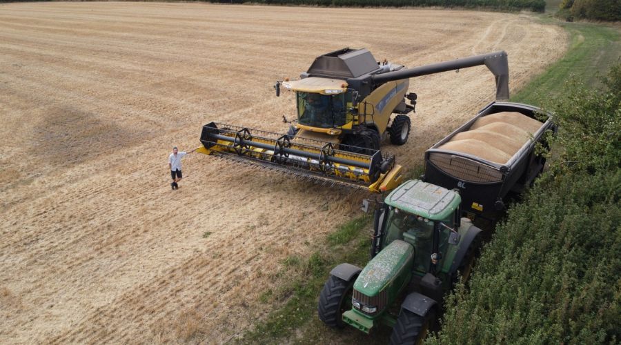 drone shot of Richard Heady standing next to combine in harvested field