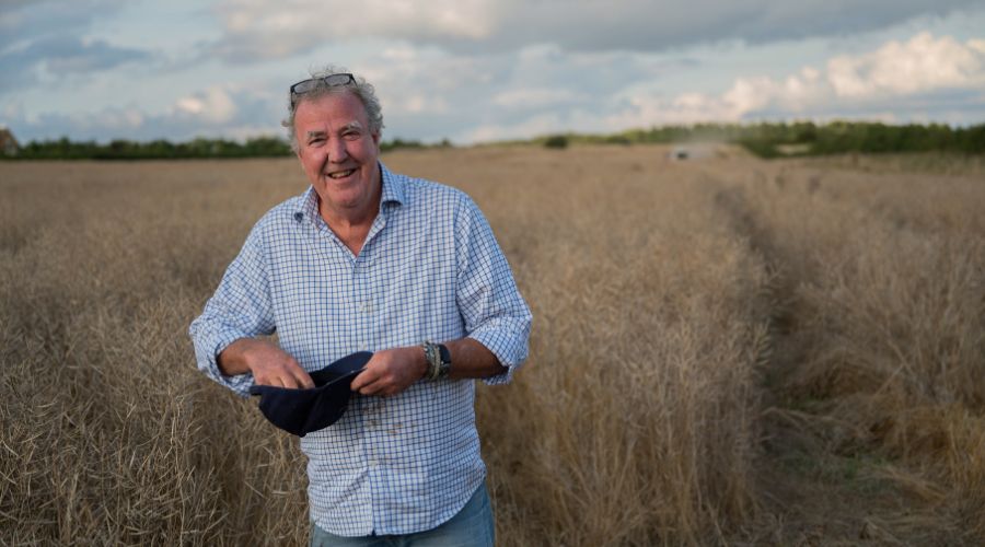 Jeremy Clarkson smiling in a field holding a hat