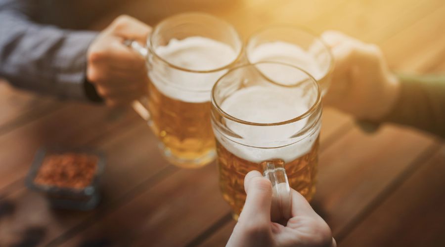 three people clinking glasses of beer together