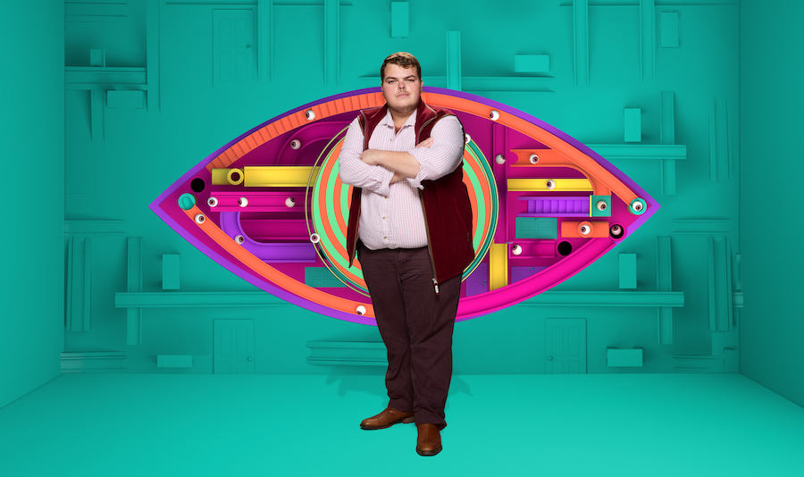 Cameron Kinch standing against green background and big brother eye 