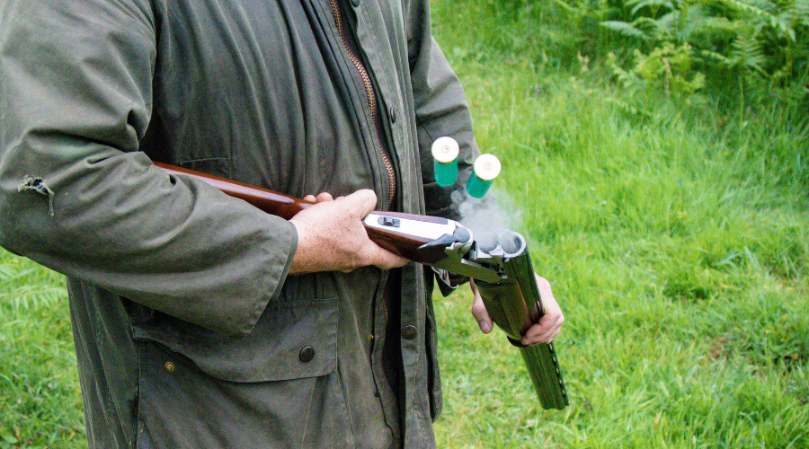 close up of shotgun being held by farmer in rainproof jacket