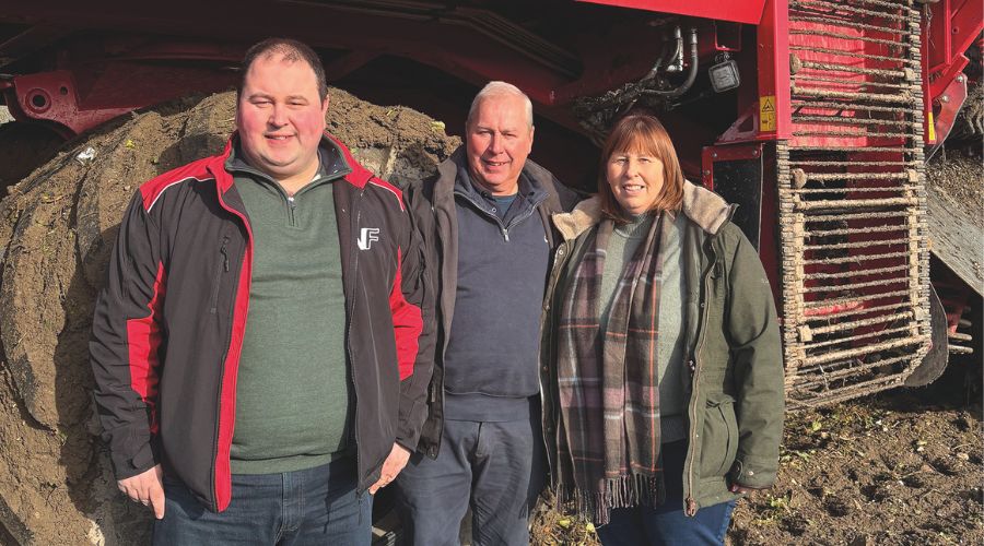 Three members of the same family infront of a beet harvester machine
