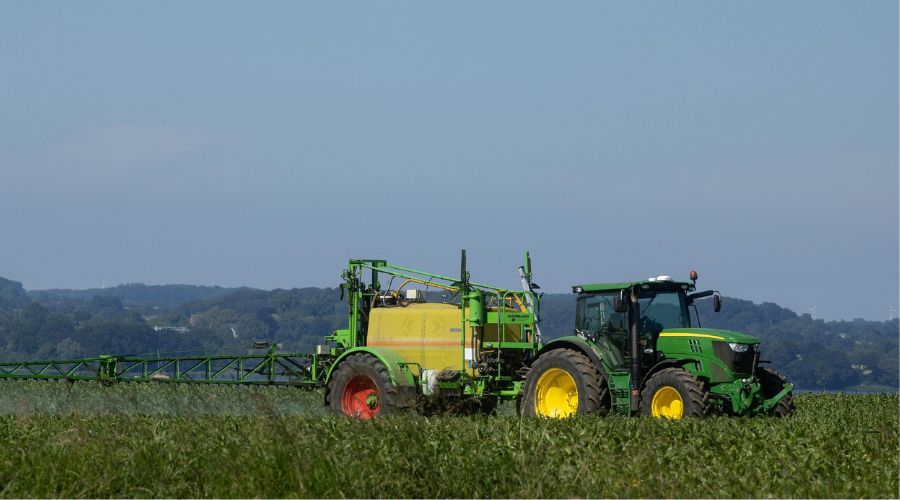 Tractor in field with sprayer attachment in use