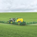 tractor with tailed sprayer spraying field